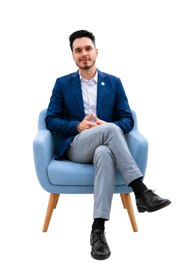 Rafael Giupponi sentado em uma poltrona azul, vestindo blazer azul
